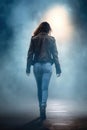 pretty urban woman wearing blue jean pants and brown leather jacket. foggy background.