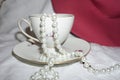 Pretty vintage teacup and saucer with pearl bead necklace spilling out Royalty Free Stock Photo