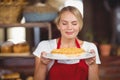 Pretty waitress smelling a plate of cake Royalty Free Stock Photo