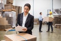 Pretty warehouse manager writing on clipboard