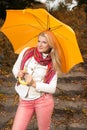 Pretty woman in autumn park with yellow umbrella