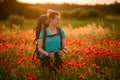 Pretty woman with backpack and walking sticks stands on field of poppies and looks away Royalty Free Stock Photo