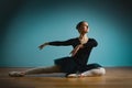 Pretty woman ballerina in tutu and pointe in black swimsuit posing in studio on blue background Royalty Free Stock Photo