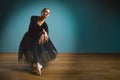 Pretty woman ballerina in tutu and pointe in black swimsuit posing in studio on blue background Royalty Free Stock Photo