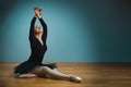 Pretty woman ballerina in tutu and pointe in black swimsuit posing in studio on blue background Royalty Free Stock Photo