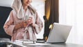 Pretty woman in bathrobe using laptop at table with partner in background at home in the kitchen Royalty Free Stock Photo