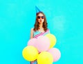 Pretty woman in a birthday cap is sends an air kiss holds an air colorful balloons Royalty Free Stock Photo