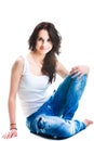 Pretty woman in blue jeans sitting on white floor