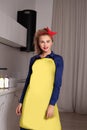 Pretty woman in blue and yellow dress in the kitchen. Pinup housewife with trendy makeup