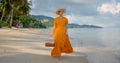 Pretty woman carrying picnic basket walking along sandy beach on a hot summer day enjoying fine view