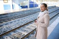 Pretty woman in casual wear, waiting for train on a railway station, checking mobile phone and looking into the distance Royalty Free Stock Photo