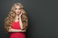 Pretty woman celebrity with makeup and blonde curly hairstyle in red evening dress on black background Royalty Free Stock Photo