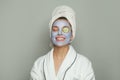 Pretty woman with cucumber slices on her eyes and moisturizing cosmetic face mask on her face. Facial treatment and skin care