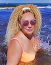 Pretty woman with curly hair in a bright swimsuit and sunglasses splashing in the waves of the Baltic Sea in Jurmala, Latvia. Royalty Free Stock Photo