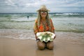 Pretty woman with curly hair and a hat holds in her hands a huge shell on the shore of the Indian Ocean Royalty Free Stock Photo