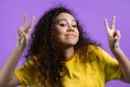 Pretty woman with curly hair showing with hands and two fingers air quotes gesture, bend fingers isolated over violet Royalty Free Stock Photo