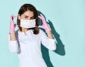 Pretty woman dentist or doctor orthodontist, nurse in medical uniform and gloves putting medical mask on face