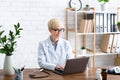 Pretty woman doctor in office at table with laptop Royalty Free Stock Photo