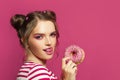 Pretty woman with donut and tongue lick one`s lips on colorful pink background Royalty Free Stock Photo