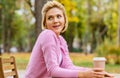 Pretty woman drinking coffee at the terrace cafeteria in the park. Blonde female in the city street drinking a hot beverage,