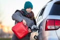 Pretty woman a driver trying to pour diesel in tank of her suv from plastic can, accident on the road at winter season Royalty Free Stock Photo