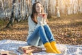 Pretty woman is eating pizza and drinking hot tea in an autumn Park at sunset. Cozy lifestyle in the autumn cold season Royalty Free Stock Photo