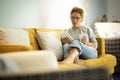 Pretty woman enjoy relax at home reading a book on tabler reader and drinking a tea or coffe sitting on a yellow sofa in living Royalty Free Stock Photo