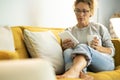 Pretty woman enjoy relax at home reading a book on tabler reader and drinking a tea or coffe sitting on a yellow sofa in living Royalty Free Stock Photo