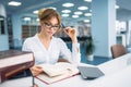 Pretty woman in glasses learning book, library Royalty Free Stock Photo