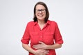 Pretty woman in glasses and red shirt with stomach pain on white background Royalty Free Stock Photo