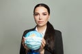 Pretty woman with a globe earth in medical protective mask on gray background