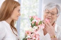 Pretty woman greeting mother with flowers smiling Royalty Free Stock Photo