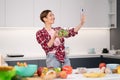 Pretty woman happy taking selfie using her smartphone while cooking fresh salad wearing a plaid shirt with a bob hair Royalty Free Stock Photo
