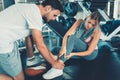 Pretty Woman Having Injury During Exercise in Gym While Her Couple Taking First Aid, Accident and Sport Fitness Concept