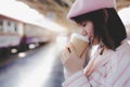 Pretty woman hold coffee cup, drink hot black coffee in morning during waiting the train at train station Royalty Free Stock Photo