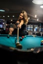 pretty woman holding cue and sits on the edge of billiard table Royalty Free Stock Photo