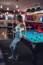 pretty woman holding cue and sits on the edge of billiard table Royalty Free Stock Photo