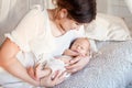 Pretty woman holding a newborn baby in her arms. Happy mother and her slipping newborn baby in the bed Royalty Free Stock Photo