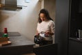 Pretty woman holding stainless steel pan, standing at kitchen counter in the minimalist home kitchen interior Royalty Free Stock Photo