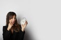 Pretty woman holding white vintage alarm clock over empty white color background.