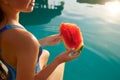 Pretty woman holds slice red watermelon stretching long tanned legs over blue pool, relaxing on tropical island in Royalty Free Stock Photo