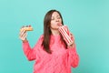 Pretty woman in knitted pink sweater with closed eyes hold in hands eclair cake, plastic cup of cola or soda isolated on