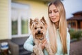 Pretty woman with long blonde hair holding small dog yorkshire terrier outdoor Royalty Free Stock Photo