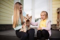 Pretty woman with long blonde hair holding small dog yorkshire terrier outdoor, next sitting little girl. Happy Mother and Royalty Free Stock Photo