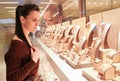 Pretty woman looking at jewelry in store window. Customer near jewellery. Dreamy long haired girl chooses silver, gold, diamonds,