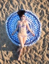 Pretty woman lying on a mandala round beach tapestry.