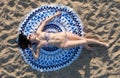 Pretty woman lying on a mandala round beach tapestry.
