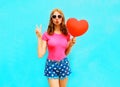 Pretty woman makes an air kiss holds a red balloon in the shape Royalty Free Stock Photo