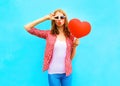 Pretty woman makes an air kiss with a red balloon in the shape Royalty Free Stock Photo
