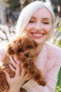 Pretty woman with a MALTIPOO dog. Adorable toy MALTIPOO puppy in arms of its loving owner. Small adorable doggy with funny curly